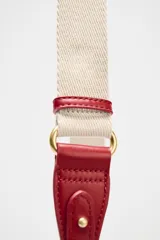 Bolso bandolera rígido color rojo, con asa corta y correa larga de tejido tipo canvas. Cierre con solapa e imán y bolsillo interior con cremallera.