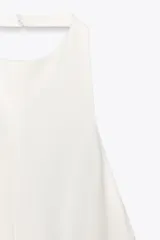 Mono largo blanco de cuello halter con botones y espalda descubierta. Pierna ancha y cierre trasero con cremallera oculta.