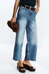 Pantalón de jean azul de corte culotte, tiro alto, pernera ancha y corta. Incluye cinturón marrón de gamuza con hebilla metálica.
