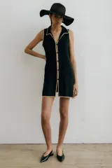 Vestido corto negro con cuello camisero, sin mangas, abotonado al frente y con aberturas laterales.