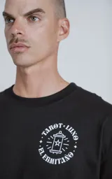 Remera negra de manga corta con cuello redondo y calce oversize. Estampa en el frente con diseño de la carta del tarot 'El Ermitaño'.