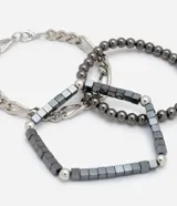 Set de tres pulseras de metal plateado y negro, con diferentes diseños: una de cadena gruesa, una de esferas y una de eslabones.