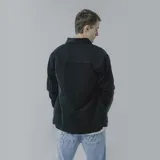 Campera negra de pana con cuello camisero, cierre frontal con botones a presión, dos bolsillos de parche en el pecho y corte recto.