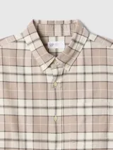 Camisa manga larga a cuadros beige, blanco y negro, con cuello abotonado y bolsillo en el pecho.