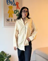 Camisa a rayas verticales amarillas y blancas, de corte holgado y mangas largas.