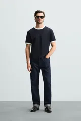 Camiseta azul marino de corte regular, con cuello redondo y mangas cortas. Presenta ribete blanco en cuello y mangas.