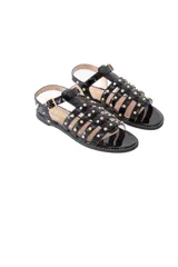 Sandalias negras de charol con tachas doradas y hebilla lateral.