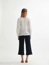 Camisa blanca de manga larga con tejido broderie (ojales bordados) y cuello camisero.