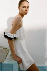 Vestido corto blanco con tirantes finos ajustables, escote recto, detalle de bordados y volantes, tejido elástico tipo nido de abeja y forro interior combinado a tono.