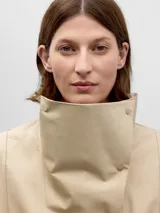 Camisa beige de algodón con cuello chimenea y cierre lateral con cuatro broches a presión. Manga japonesa con corte en la sisa en la espalda y puño con abertura y broche.