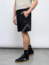 Bermuda deportiva negra de algodón y poliéster, con cintura elástica ajustable con cordón, bolsillos laterales y detalle de recortes geométricos en gris en los laterales. Logo de la marca bordado en la pierna izquierda.