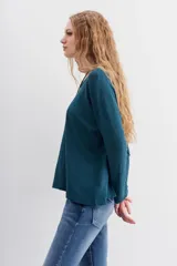 Remera blanca de algodón con calce relajado y cuello redondo. Tiene mangas largas que se ajustan hacia los puños.