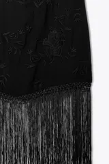 Vestido corto negro con cuello halter y espalda descubierta. Presenta bordados florales a tono y terminación con flecos.