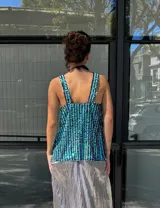 Musculosa con escote en V y breteles anchos, confeccionada en tela de lentejuelas color turquesa y verde.