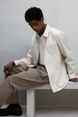 Pantalón jogger de vestir color beige, corte slim fit, con cintura elástica ajustable con cordón, pliegues delanteros y traseros, bolsillos laterales al bies y bolsillos traseros insertados.