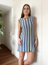 Vestido corto de algodón tejido en punto jersey con diseño de rayas verticales rojas y blancas. Terminaciones en crochet hechas a mano con detalle de lurex. Cuello redondo, sin mangas y silueta trapecio.