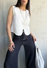 Chaleco blanco con botones al frente y corte irregular en el ruedo.