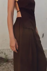 Pantalón marrón de tiro alto con cintura elástica en la espalda, bolsillos laterales, pliegues en la parte delantera y bordados combinados a tono en el ruedo.