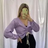 Remera de manga larga color lila con escote en V y frunce central ajustable con cordones.