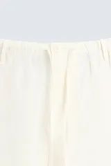 Pantalón de lino color crudo, de corte ancho, con cintura elástica ajustable con cordón, bolsillos laterales y trasero.