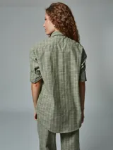 Camisa de manga larga color ladrillo con rayas blancas, confeccionada en lino. Tiene cuello clásico, cierre frontal con botones y bolsillo de parche en el pecho.