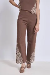Pantalón blanco de corte ancho con bordados calados en forma de hojas en el ruedo.