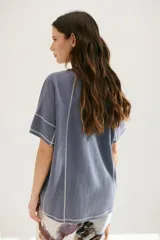 Remera azul de corte holgado con mangas cortas y costuras a la vista en color blanco.