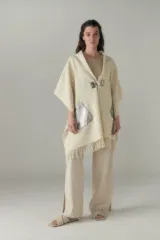 Chal de lana fina sin teñir, con calce en hombros, abrochadura con alamar de fieltro, bolsillos de cuero y terminación con flecos. Diseño exclusivo de Don Baez, hecho en Uruguay.