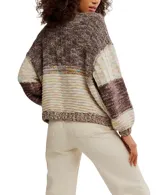 Cárdigan grueso de punto con diseño patchwork en tonos marrones, beige y toques de color pastel. Presenta cuello V, botones frontales y bolsillos amplios en la parte delantera. Las mangas son largas y abullonadas.