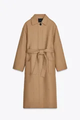 Abrigo largo color camel confeccionado en hilatura con lana. Tiene cuello clásico, cierre frontal con botones ocultos, bolsillos de parche y cinturón del mismo tejido.