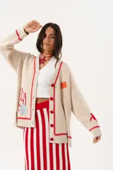 Saco oversize tejido con ilustraciones inspiradas en corales, peces, estrellas de mar y tortugas. Presenta galón picot en rojo en cartera y puños, y botones a tono.