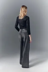 Jean oxford de tiro alto confeccionado en denim negro rígido con lavado stone y bigotes. Pierna ancha desde la cadera.