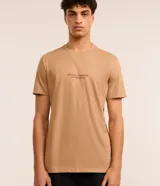 Remera color beige de algodón, corte comfort, con cuello redondo y mangas cortas. Presenta estampa de montañas y texto "Silence is louder in the wild".