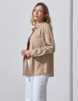 Camisa blanca de lyocell, marca Dash. Tiene cuello con solapa, abertura central con botones, mangas largas regulables con presilla y botón, y dos bolsillos delanteros aplicados.