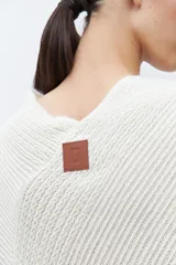 Capa tejida color negro, con cuello redondo, diseño de punto y detalles de lentejuelas. Presenta flecos en el dobladillo.