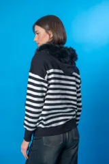 Sweater con capucha a rayas horizontales blancas y negras, con cuello de piel sintética negra y cordón de perlas con pompones de piel sintética negra.