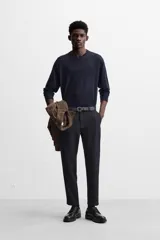 Pantalón slim fit negro confeccionado en tejido con elasticidad en ambas direcciones. Cuenta con bolsillos frontales y traseros de vivo con botón. Cierre frontal con cremallera y botón.