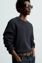 Camiseta blanca de manga larga con cuello redondo y textura cuadriculada.