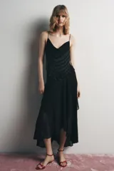 Vestido midi negro de tirantes finos con escote fluido y detalle de abalorios en el corpiño. Falda asimétrica con volados. Forro interior.