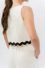 Top de lino color crudo, con escote cuadrado y detalle de guarda ondulada negra en el ruedo.