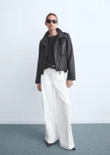 Pantalón de jeans blanco, tiro alto, corte wideleg (pierna ancha) y largo. Presenta bolsillos de parche en la parte delantera y bolsillos traseros.