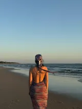 Vestido largo con estampado abstracto en tonos rojizos y celestes, escote drapeado profundo y tirantes finos.