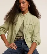 Campera bomber color verde claro, con cierre delantero, bolsillos con solapa y pespuntes contrastantes.
