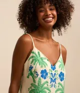 Vestido corto con breteles finos y escote en V, confeccionado en viscosa y lino. Presenta una estampa tropical con palmeras verdes, flores azules y dos aves azules enfrentadas. El ruedo tiene una franja azul con un detalle verde.