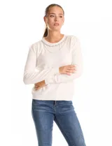 Buzo tejido en hilado fino, color blanco, con escote a la base y un collar decorativo de perlas y strass. Tiene mangas largas con un leve frunce en los hombros.