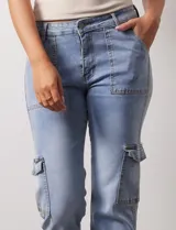 Pantalón jean celeste con bolsillos cargo laterales, pretina con pasadores, botón y cierre.