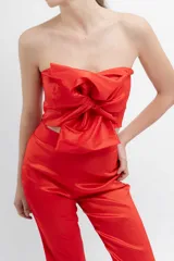 Top strapless en tafeta elastizada color verde oscuro, con moño frontal y cierre lateral para mayor comodidad.