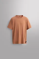 Camiseta color ladrillo de corte holgado, cuello redondo y manga corta. Tiene un pequeño logo estampado en la parte inferior.