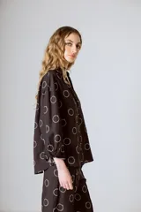 Camisa marrón con estampado de círculos blancos, cuello mao, manga larga y cierre frontal con botones.