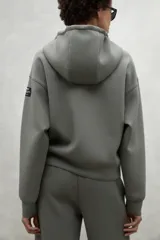 Campera gris con capucha ajustable con cordones, cierre frontal y bolsillos laterales.